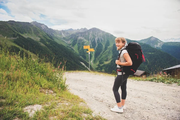 Menina feliz caminhando em Alpes suíços, usando mochila preta, viajar com crianças. Imagem tirada no cantão de Valais, Suíça — Fotografia de Stock