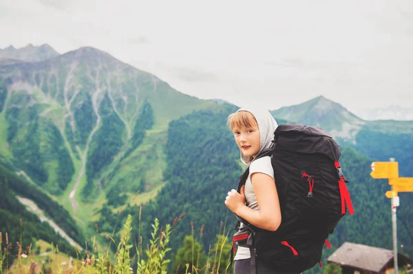 Fröhliches kleines Mädchen, das in den Schweizer Alpen wandert, schwarzen Rucksack trägt und mit Kindern unterwegs ist. Aufnahme aus dem Kanton Wallis, Schweiz — Stockfoto