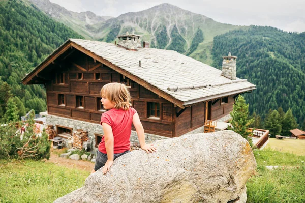Menino caminhando nas montanhas, sentado na rocha e admirando uma vista incrível. Imagem tirada no cantão de Valais, Suíça. Visão traseira — Fotografia de Stock