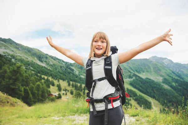 Happy little girl hiking in swiss Alps, wearing black backpack, travel with kids. Image taken in canton of Valais, Switzerland — Stock Photo, Image
