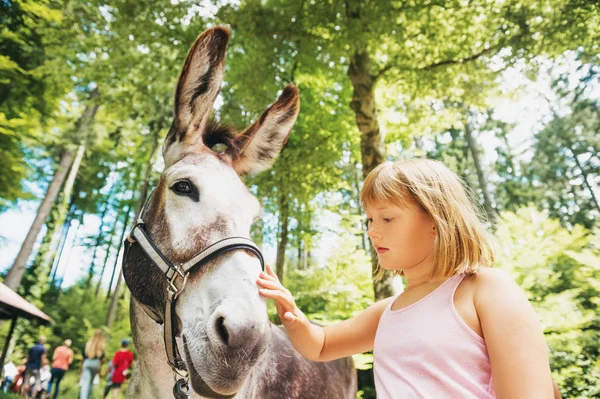 Kleines Mädchen wandert mit Eseln im Kinderferienlager — Stockfoto