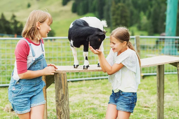 Fetițele mici se joacă cu capre în timpul vacanței de vară în terenul agricol — Fotografie, imagine de stoc