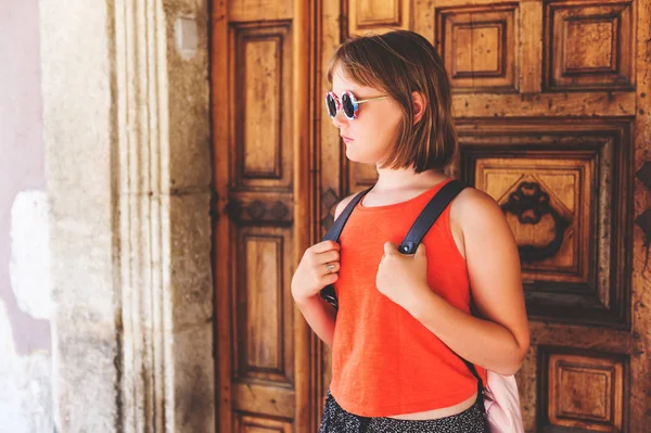 Funny little girl traveler walking on the streets of Provence, wearing backpack. Travel with kids, family vacation on south of France, image taken in Aigues-Mortes, Camargue Stock Picture