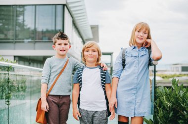 Açık havada poz, sırt çantaları giyen 3 komik schoolkids grubudur. Geri okul kavramı. Çocuklar için moda