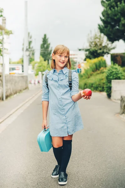 Resmi elbise ve sırt çantası takmış, beslenme çantası ve Kırmızı elma tutan komik liseli kızlar, açık portresi. Geri okul kavramı, göz film için görüntü tonda