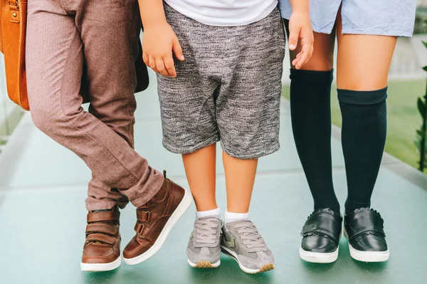 Fashion schoenen op kinderen. Drie paren van kinder voeten dragen comfortabel en mode trainers. Terug naar school concept — Stockfoto