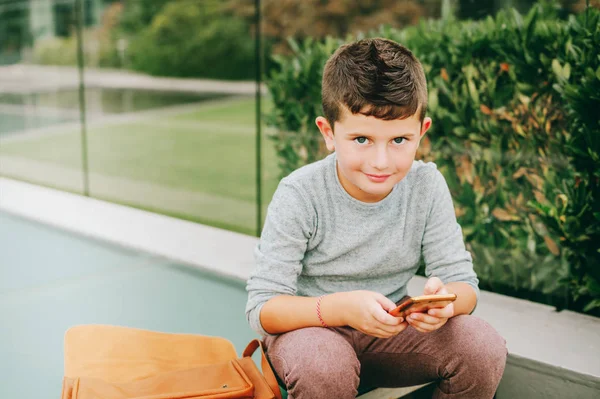 Ritratto all'aperto di carino scolaretto che gioca con lo smartphone — Foto Stock