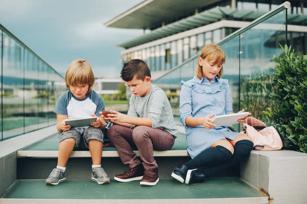 Gruppo di 3 simpatici bambini che giocano con tablet pc all'aperto. Bambini piccoli che utilizzano gadget elettronici — Foto Stock