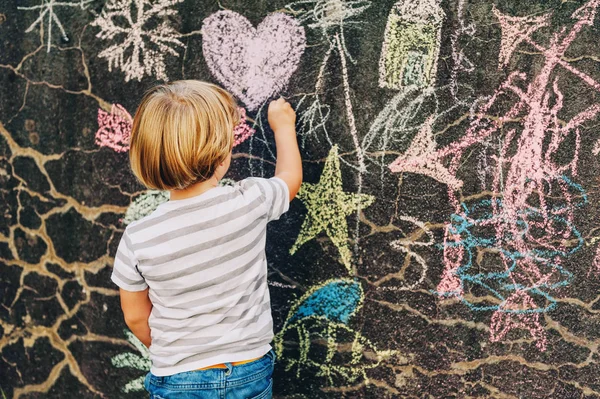 可爱的小男孩用一支粉笔在户外绘图。孩子们的的课外活动。后视图 — 图库照片
