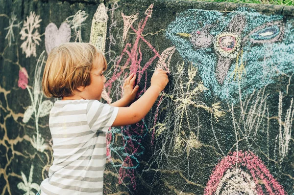 Adorável menino desenhando com um giz ao ar livre. Atividades externas para crianças — Fotografia de Stock