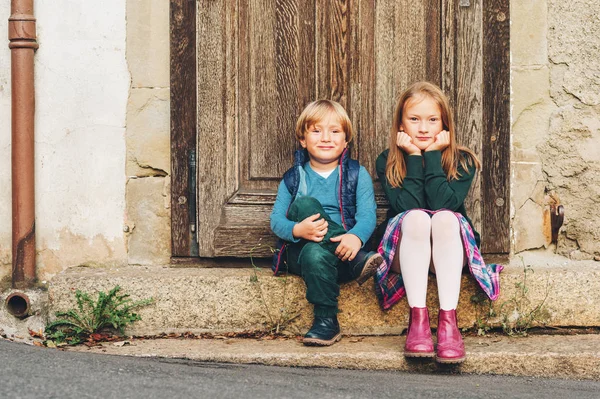Grupp två snygga barn poserar utomhus, vilar bredvid gamla vintage dörr. Mode för schoolkids. Skor och kläder för skolan. Liten pojke och flicka som leker tillsammans — Stockfoto