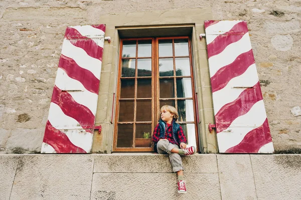 Plenerowej zabawny mały chłopiec siedzący o okna, na sobie buty do tenisa — Zdjęcie stockowe