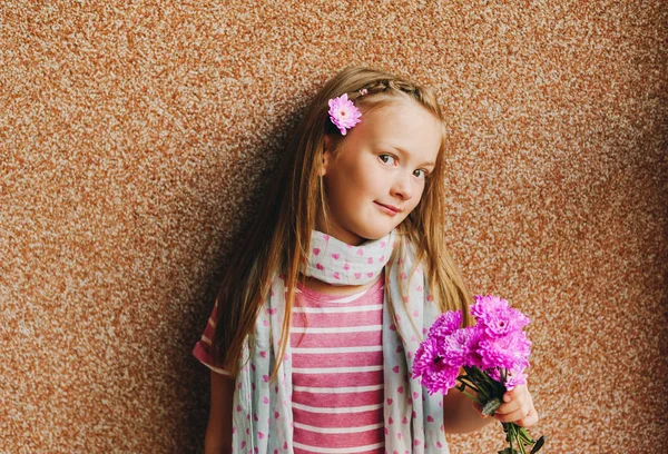 Candid portrait of adorable little 6-7 year old girl holding pink chrysanthemum flower — Stock Photo, Image