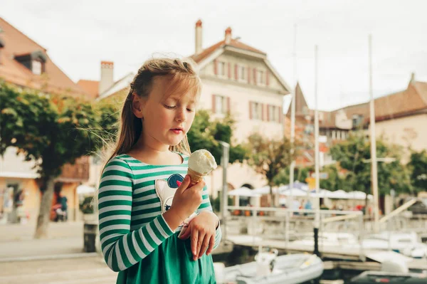 Портрет забавной маленькой девочки, поедающей мороженое у озера — стоковое фото