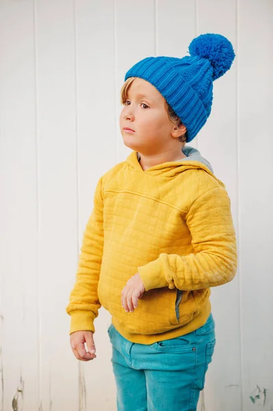 Elegante menino de 5 anos de idade usando chapéu azul, amarelo (açafrão ou cor de mostarda) com capuz e jeans ciano — Fotografia de Stock