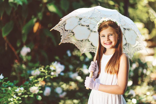 Outdoor portrait of romantic little girl, wearing white dress, gloves, flower headband, holding lace umbrella — Stock Photo, Image