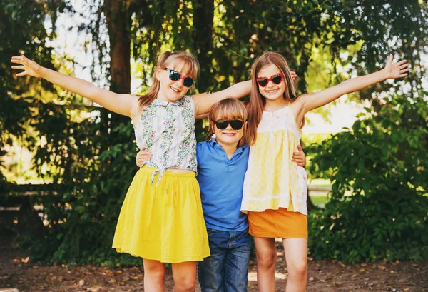 На відкритому повітрі портрет трьох смішних дітей, які грають разом у літньому парку. Щасливе дитинство — стокове фото
