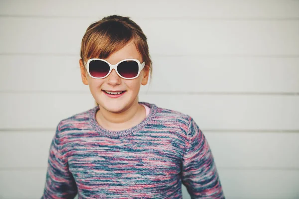 Fashion portrait of pretty little girl wearing sunglasses and purple pullover — Stock Photo, Image