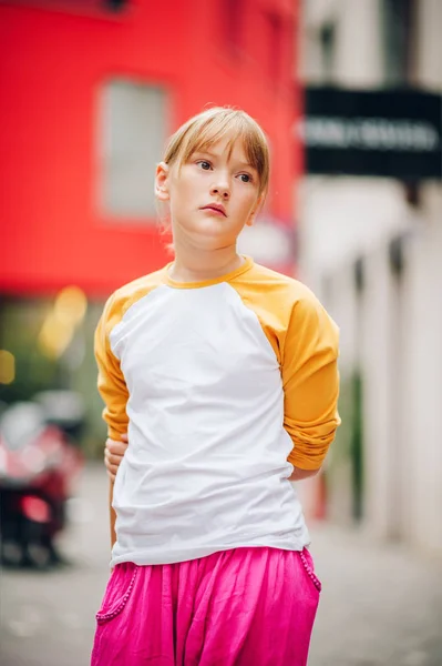 예쁜 십 대 소녀의 도시에서 야구 노란색과 흰색 긴 소매를 입고 야외 초상화 티셔츠와 밝은 핑크 바지 — 스톡 사진