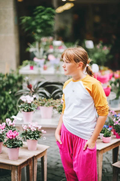 Kültéri álló szép kis tizenéves lány egy városban, visel baseball sárga és fehér hosszú ujjú póló és világos rózsaszín nadrág — Stock Fotó