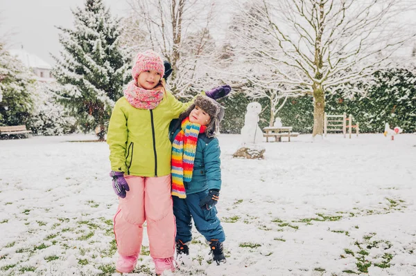 Dvě rozkošné děti spolu hrají ve Snowparku, teplé zimní oblečení — Stock fotografie