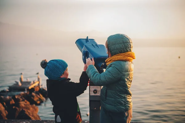 Маленькі діти, дивлячись на монета operated Бінокулярний Женевського озера в зимовий час — стокове фото