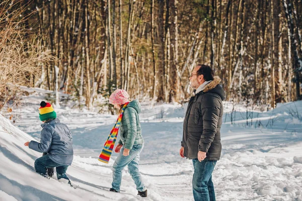 Porträtt av far och två barn njuter av vintern skog på en fin solig dag — Stockfoto