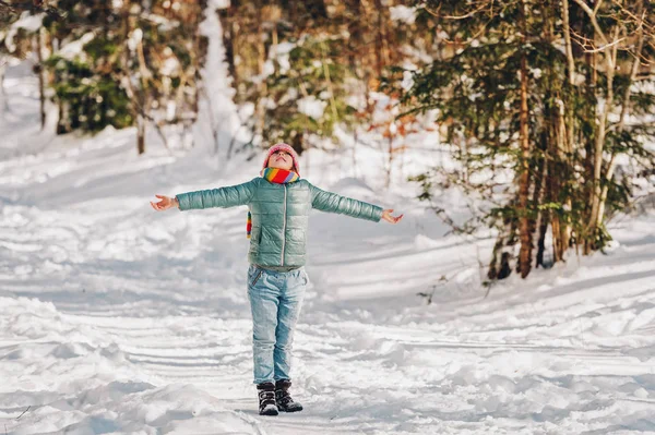 Utomhus porträtt av vackra lilla flicka som leker i vinter skog, bär färgglada halsduk och hatt — Stockfoto