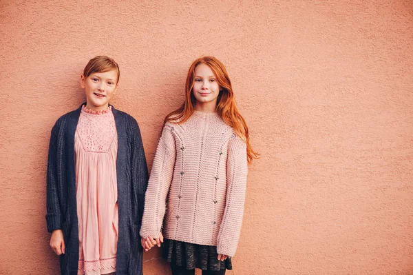 Retrato de duas meninas pré-adolescentes bonitas vestindo pulôver de malha e casaco, amigos brincando juntos lá fora. Moda para adolescentes. Ajoelhados — Fotografia de Stock