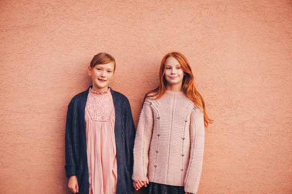 Retrato de duas meninas pré-adolescentes bonitas vestindo pulôver de malha e casaco, amigos brincando juntos lá fora. Moda para adolescentes. Ajoelhados — Fotografia de Stock