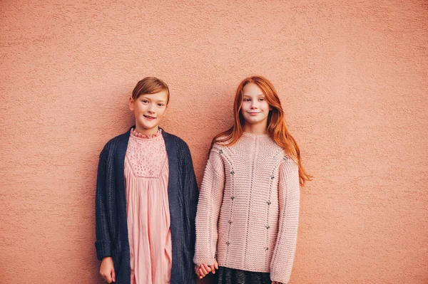 Portrait of two pretty little preteen girls wearing knitted pullover and jacket, friends playing together outside. Fashion for teens. Kneatwear — Stock Photo, Image