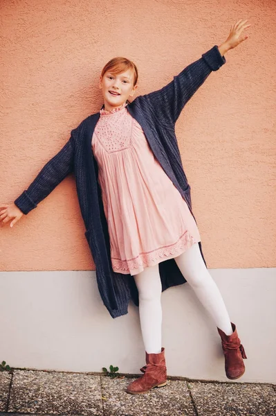 Outdoor portrait of adorable preteen girl wearing soft pink dress, kid model posing against beige wall background. Fashion for young teens — Stock Photo, Image