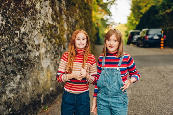 Retrato al aire libre de dos niñas preadolescentes divertidas que usan vaqueros, pulóveres de cuello rollo de rayas, moda para adolescentes —  Fotos de Stock