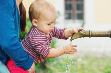 Su çeşme parkta oynarken şirin bebek. 