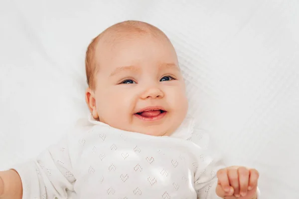 Adorável menina deitada no cobertor branco e sorrindo, vestindo corpo do coração — Fotografia de Stock