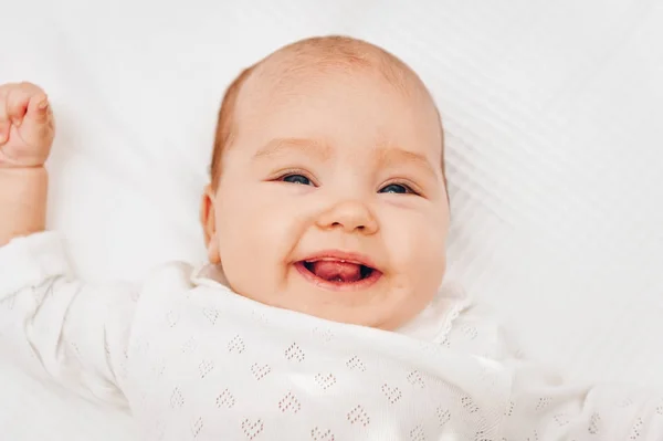 Adorable baby girl lying on white blanket and smiling, wearing heart body — Stock Photo, Image