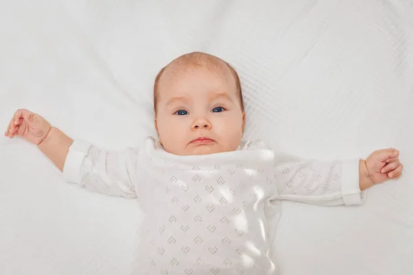 Adorável menina deitada no cobertor branco e sorrindo, vestindo corpo do coração — Fotografia de Stock