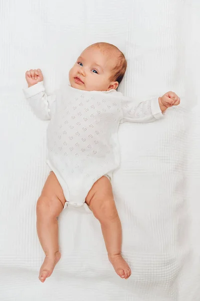 Αξιολάτρευτο μωρό κορίτσι ξαπλωμένο στο κουβέρτα λευκό και χαμογελαστός, φορώντας σώμα καρδιά — Φωτογραφία Αρχείου