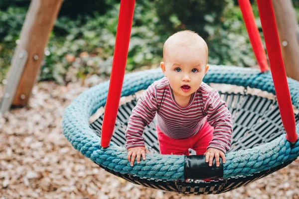 Baby girl having fun in the park, 9-12 months old kid playing in the big swing, summer playground, activities for children — Stock Photo, Image