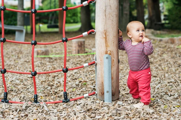 Открытый портрет восхитительной девочки, веселящейся на детской площадке, симпатичного маленького ребенка 9-12 месяцев, играющего на улице — стоковое фото