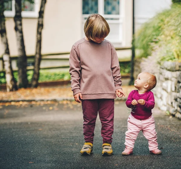 Outdoor portrait of two funny kids, little 9 month old baby girl and 6 year old boy playing together outside — Stock Photo, Image