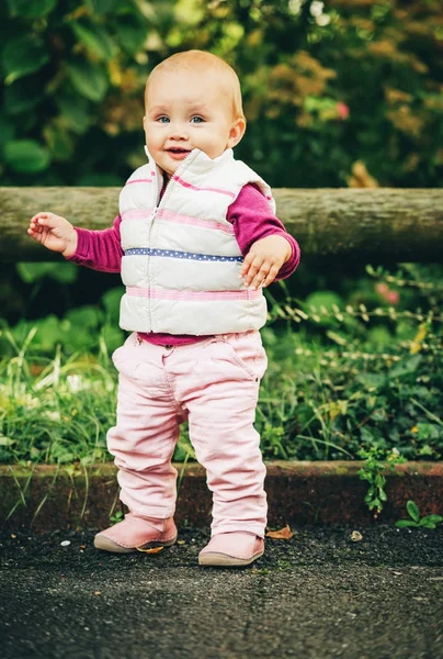 Utomhus porträtt av förtjusande baby flicka 9-12 månader gamla spelar i parken, klädd i vit bodywarmer — Stockfoto