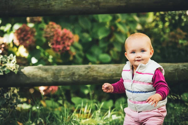 Utomhus porträtt av förtjusande baby flicka 9-12 månader gamla spelar i parken, klädd i vit bodywarmer — Stockfoto