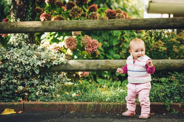Utomhus porträtt av förtjusande baby flicka 9-12 månader gamla spelar i parken, klädd i vit bodywarmer — Stockfoto