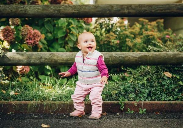 Utomhus porträtt av förtjusande baby flicka 9-12 månader gamla spelar i parken, klädd i vit bodywarmer — Stockfoto