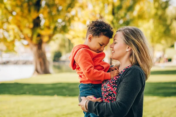 Mutlu genç anne holding tatlı yürümeye başlayan çocuk, eğlenceli birlikte güzel güneşli bir günde dışarıda olan aile — Stok fotoğraf