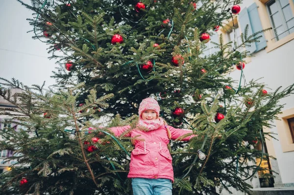 Menina feliz brincando com árvore de Natal nas ruas da antiga cidade europeia, viagem de férias com crianças, imagem tirada em Lausanne; Suíça — Fotografia de Stock