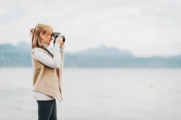 Ładny mały preteen dziewczyna cieszy ładny dzień nad Jeziorem Genewskim, Robienie zdjęć z aparatu dslr, noszenia kurtka beżowy. Podróż z dziećmi. Zdjęcie zrobione w Lozannie; Szwajcaria — Zdjęcie stockowe