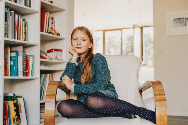 Cute little girl sitting in a white chair at home — Stock Photo, Image