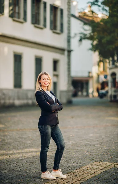 Retrato de mulher loira bonita na rua, vestindo jaqueta preta, braços cruzados — Fotografia de Stock